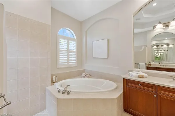 a spacious bathroom with a double vanity sink a large mirror and a bathtub