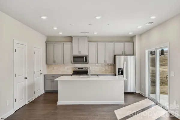 a kitchen with stainless steel appliances a refrigerator sink and white cabinets