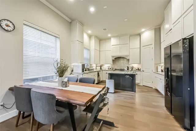 a dining room with stainless steel appliances kitchen island granite countertop a dining table chairs and a refrigerator