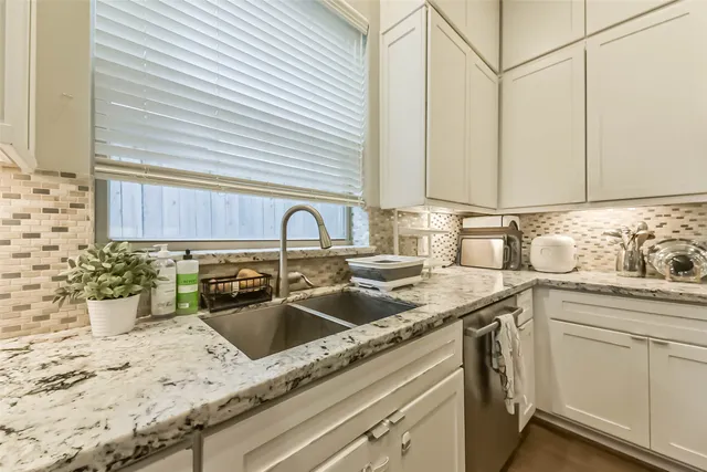 a kitchen with granite countertop a stove and a white wooden cabinets