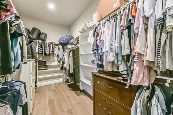 a view of walk in closet with clothes and shoes