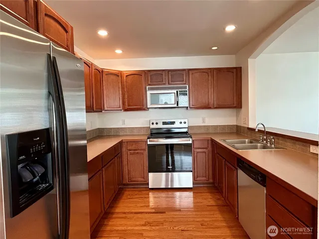 a kitchen with stainless steel appliances granite countertop a stove a sink and a refrigerator
