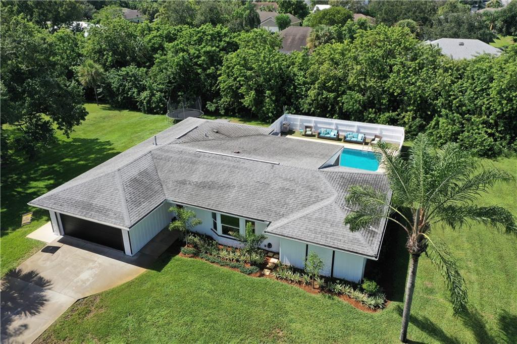 an aerial view of a house with yard and trees in the background