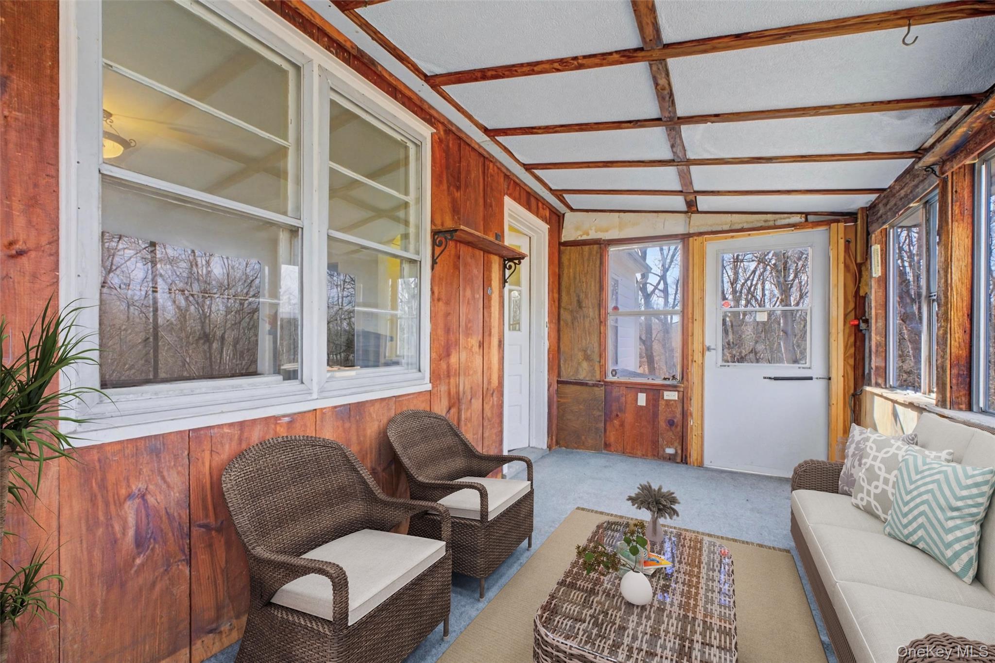 566 Old State Road Wappingers Falls, NY 12590 - Photo 13 of 19 Virtually Staged Cozy porch area highlighted by natural wood finishes and a rustic wood stove, creating a warm and inviting atmosphere during cooler months.