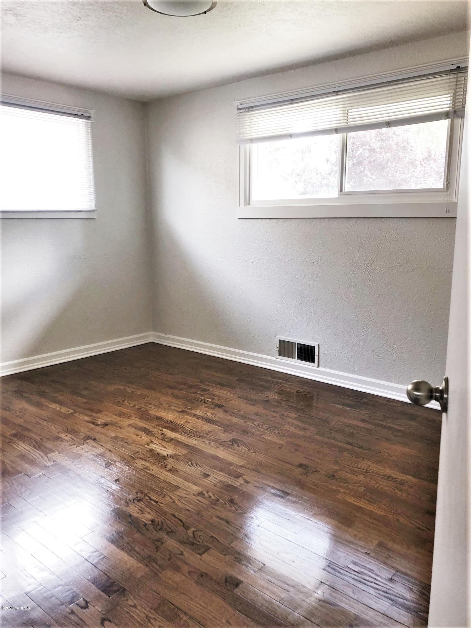 705 West Concord Avenue Grandview, WA 98930 - Photo 11 of 20 a view of an empty room with wooden floor and a window