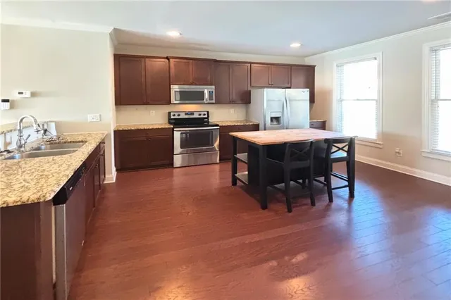 a kitchen with kitchen island granite countertop stainless steel appliances a sink a counter top space and cabinets