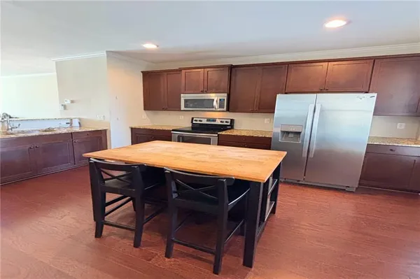 a kitchen with stainless steel appliances a refrigerator a stove a sink a dining table and chairs