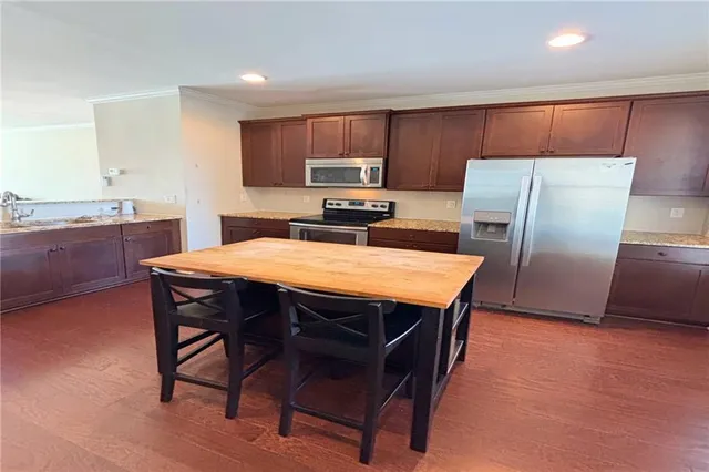 a kitchen with stainless steel appliances a refrigerator a stove a sink a dining table and chairs