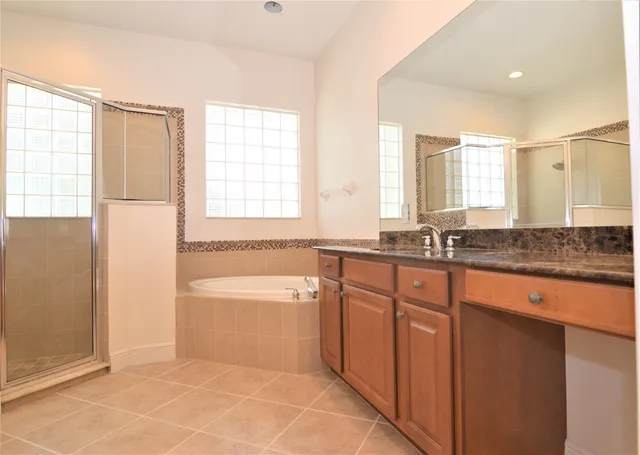 a spacious bathroom with a granite countertop tub sink and mirror