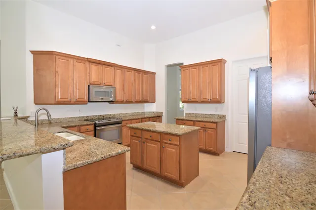 a kitchen with stainless steel appliances granite countertop a stove a sink and a refrigerator