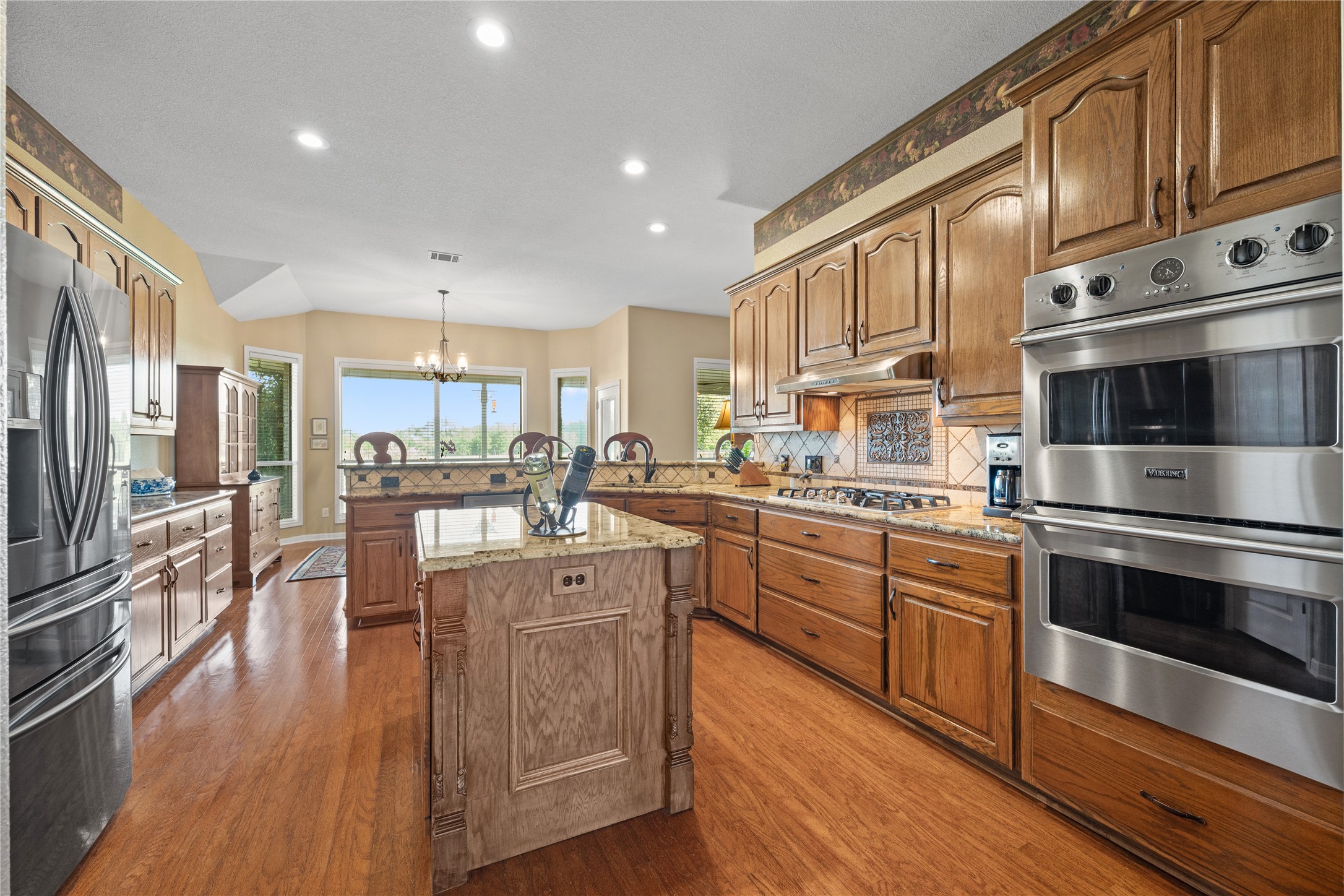266 Courtnee's Way Georgetown, TX 78626 - Photo 12 of 40 Gourmet kitchen featuring gas cooktop, a center island, Viking double ovens, custom cabinetry, and granite countertops.