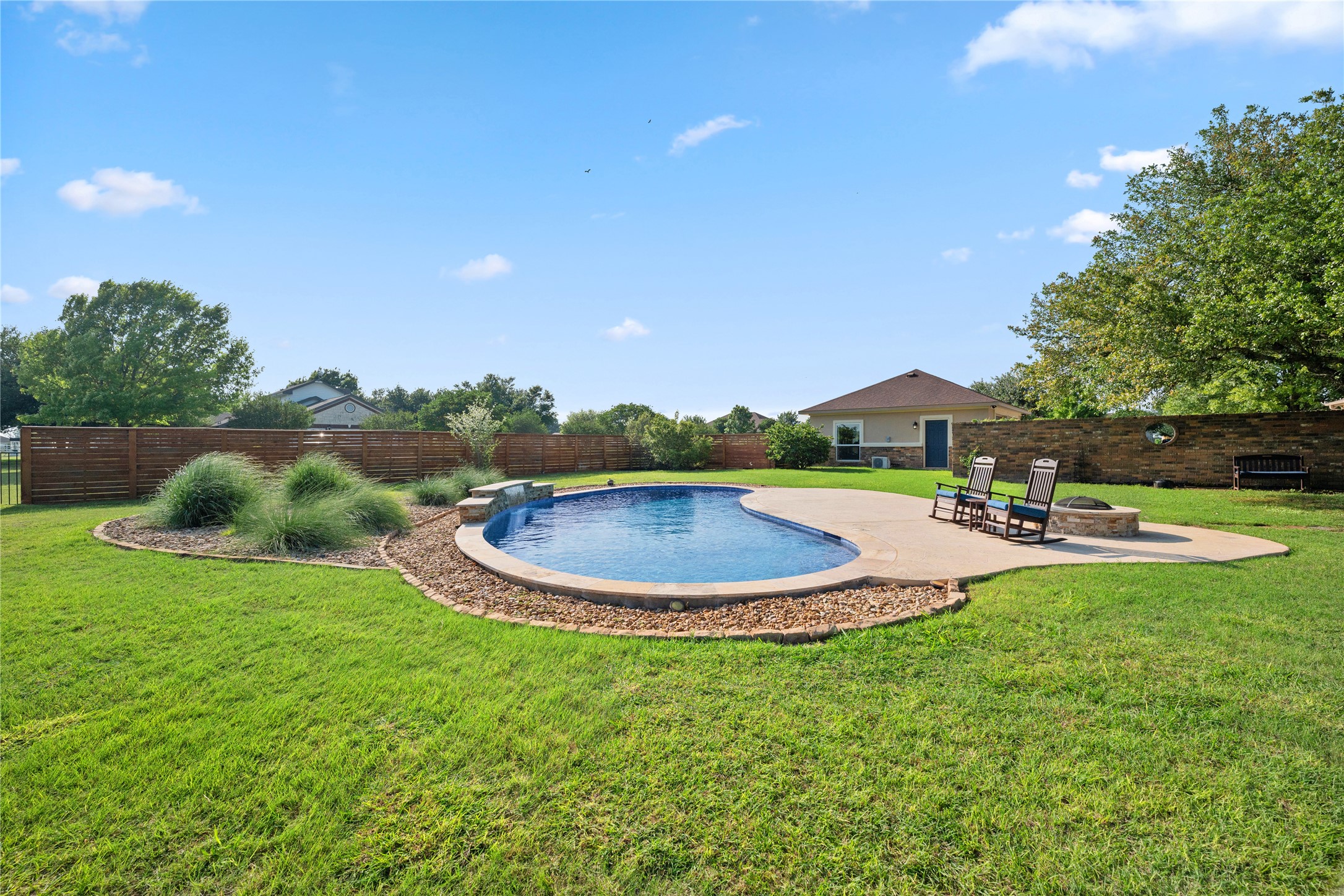 266 Courtnee's Way Georgetown, TX 78626 - Photo 31 of 40 Expansive backyard featuring a freeform swimming pool, surrounding concrete patio, and decorative landscaping