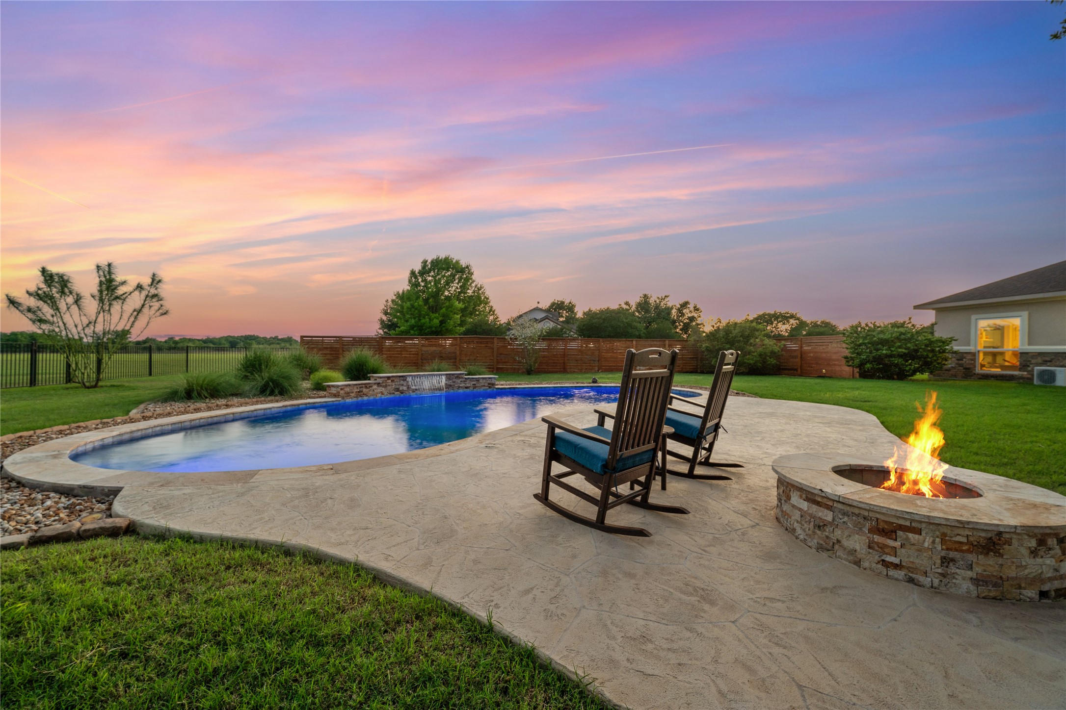 266 Courtnee's Way Georgetown, TX 78626 - Photo 32 of 40 Expansive backyard featuring a freeform swimming pool with integrated waterfall feature, a stamped concrete patio, and a stone-clad fire pit
