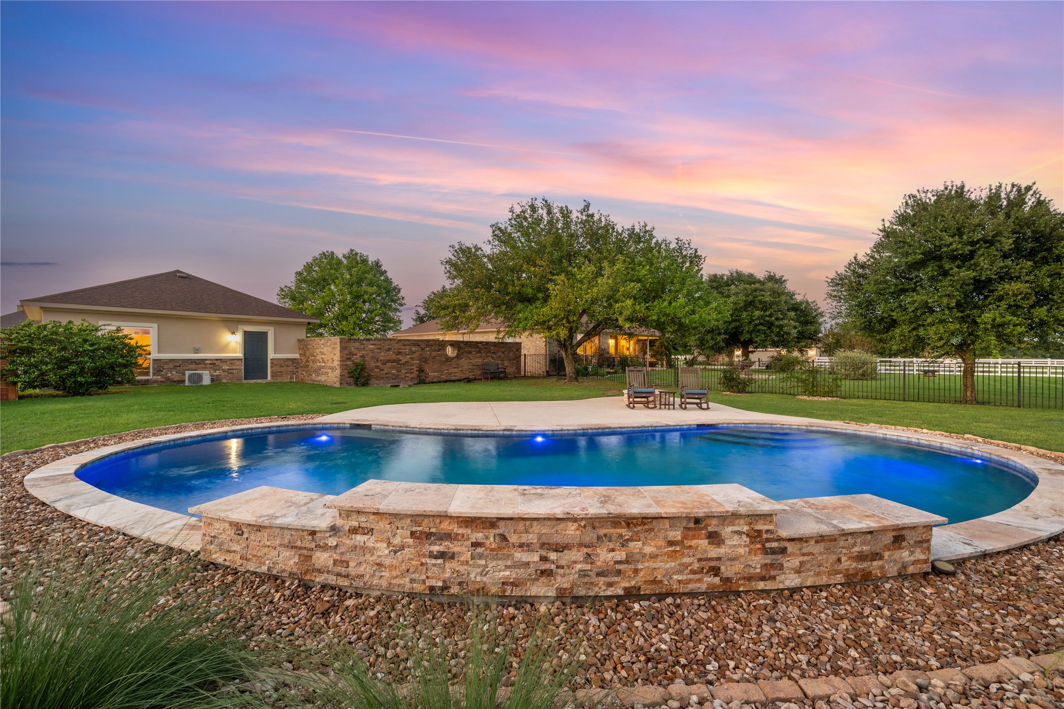 266 Courtnee's Way Georgetown, TX 78626 - Photo 35 of 40 Resort-style pool with integrated stone-clad water feature, expansive concrete decking, and brick wall for privacy.