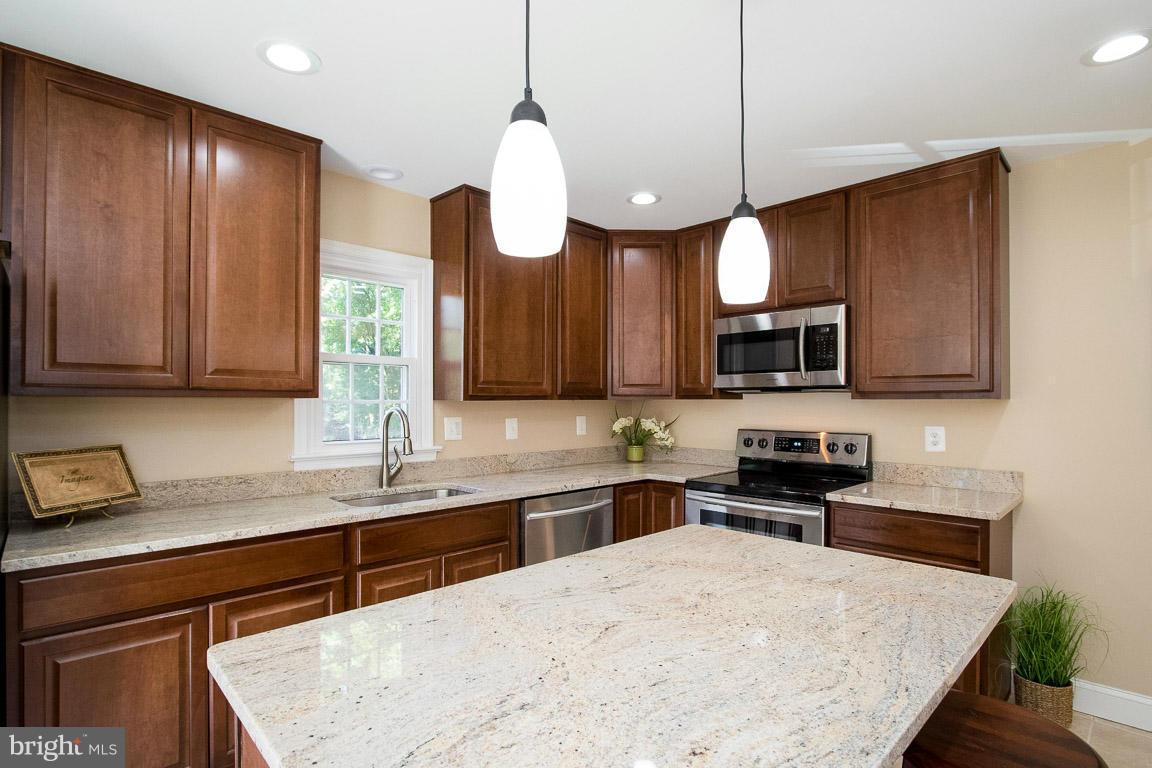 10802 Hunt Club Road Reston, VA 20190 - Photo 10 of 30 a kitchen with stainless steel appliances wooden cabinets a stove a sink and a microwave