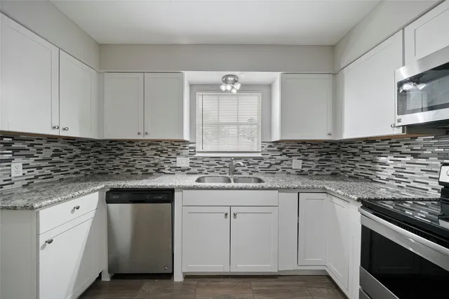 a kitchen with granite countertop white cabinets and white appliances