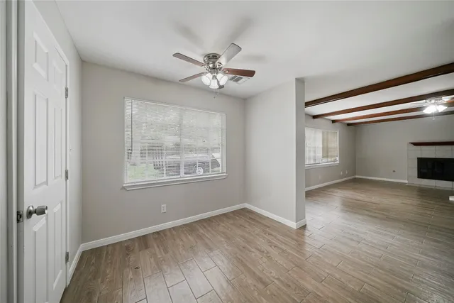 a view of empty room with wooden floor and fan