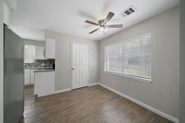 a view of an empty room with a window and wooden floor