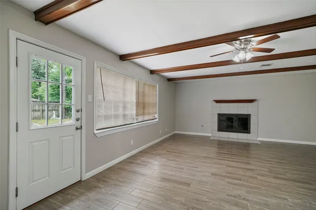 an empty room with wooden floor fireplace and windows