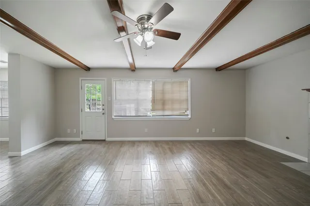 an empty room with wooden floor chandelier fan and windows