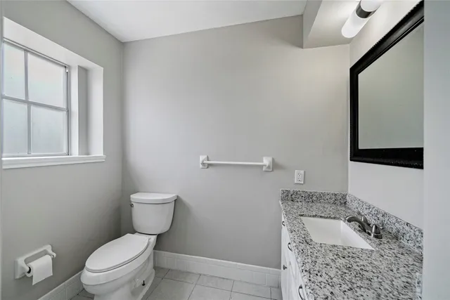 a bathroom with a granite countertop toilet and a sink
