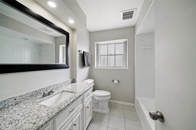 a spacious bathroom with a granite countertop sink a toilet and a mirror