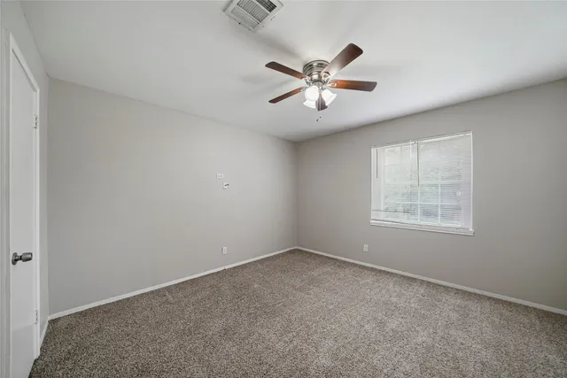 a view of an empty room with chandelier fan and a window