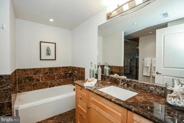 a bathroom with a granite countertop tub sink and mirror