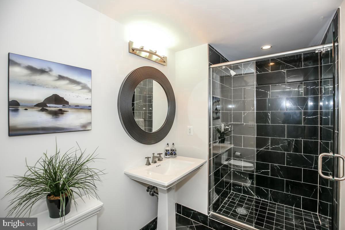 4301 Military Road Northwest, Unit 312 Washington, DC 20015 - Photo 7 of 9 a bathroom with a sink a mirror and a shower