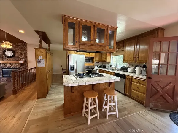 a kitchen with stainless steel appliances granite countertop a stove a sink dishwasher and a refrigerator with wooden cabinets