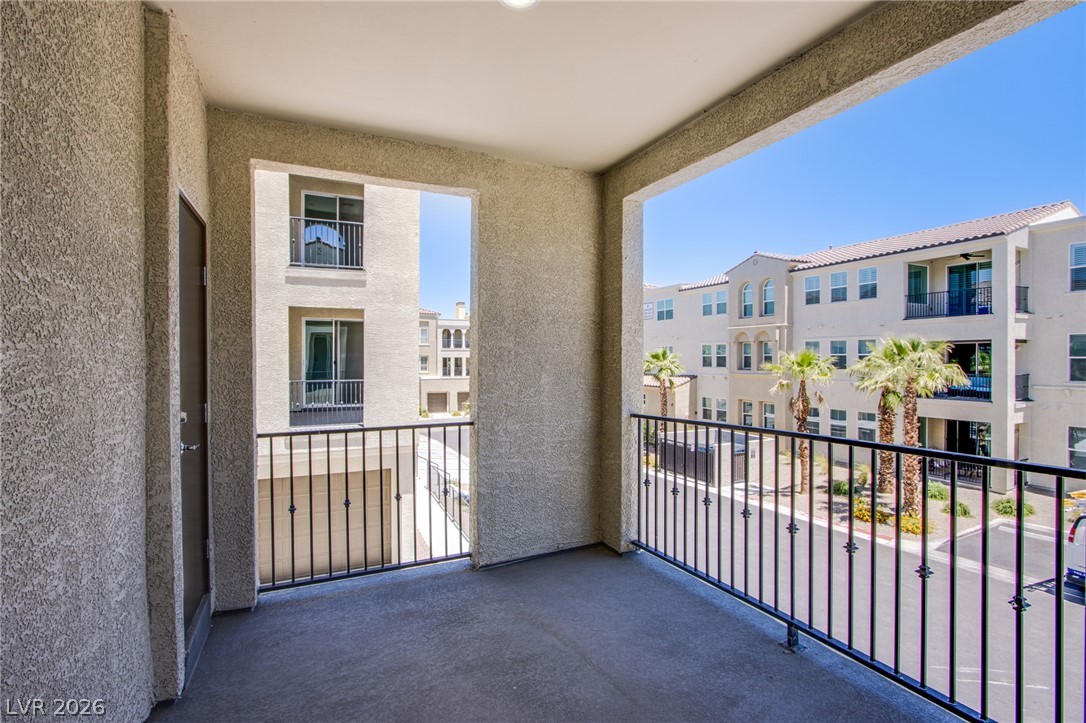 An elevated private balcony features durable concrete flooring and secure metal railings overlooking the neighborhood.