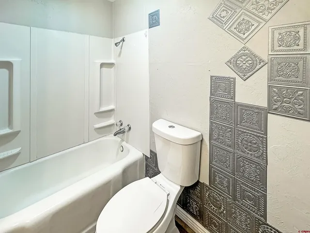 a white toilet sitting next to a bath tub