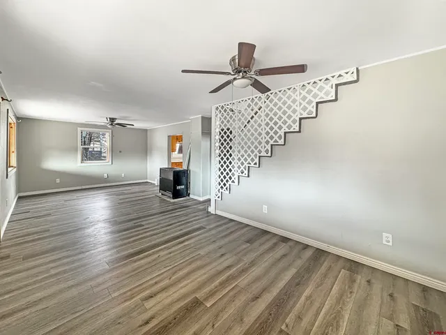 a view of an empty room with wooden floor and staircase