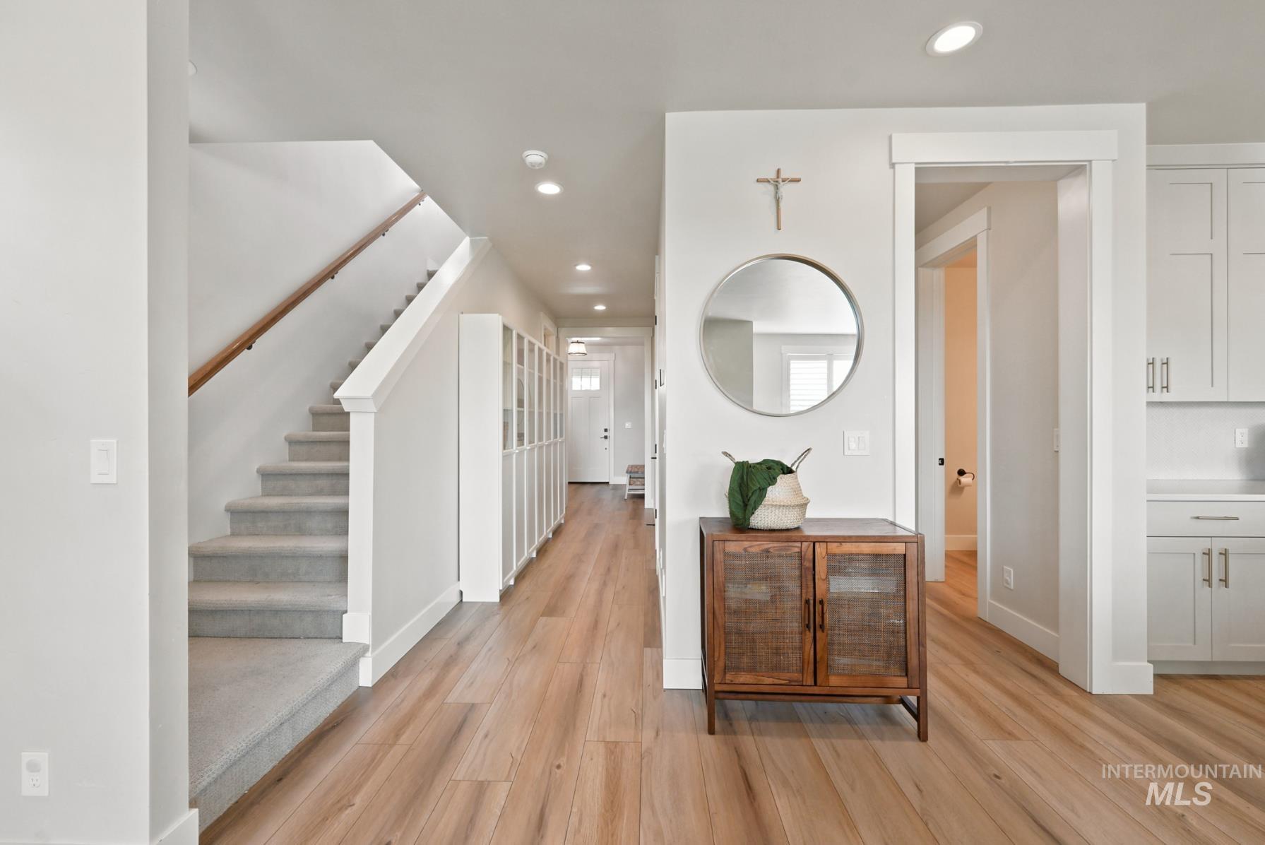 6933 South Zenith Avenue Meridian, ID 83642 - Photo 3 of 34 Bright entryway featuring wood-finish flooring, a carpeted staircase with a wood handrail, recessed lighting, and white built-in cabinetry
