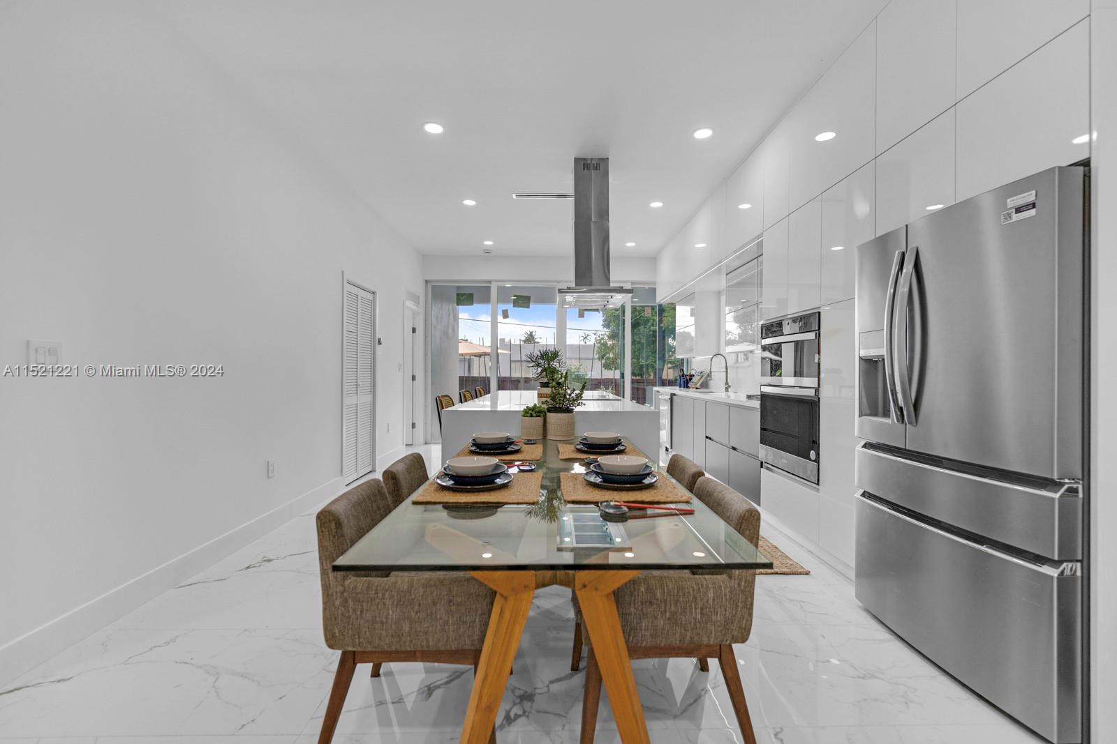2356 Southwest 11th Street Miami, FL 33135 - Photo 15 of 51 a kitchen with stainless steel appliances granite countertop a refrigerator a stove and a dining table with wooden floor