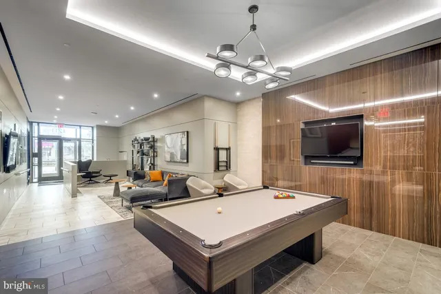 a living room with stainless steel appliances furniture a flat screen tv and kitchen view