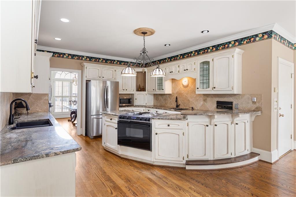 3910 Spalding Bluff Drive Peachtree Corners, GA 30092 - Photo 8 of 35 a kitchen with stainless steel appliances granite countertop a stove a sink dishwasher a refrigerator and white cabinets with wooden floor