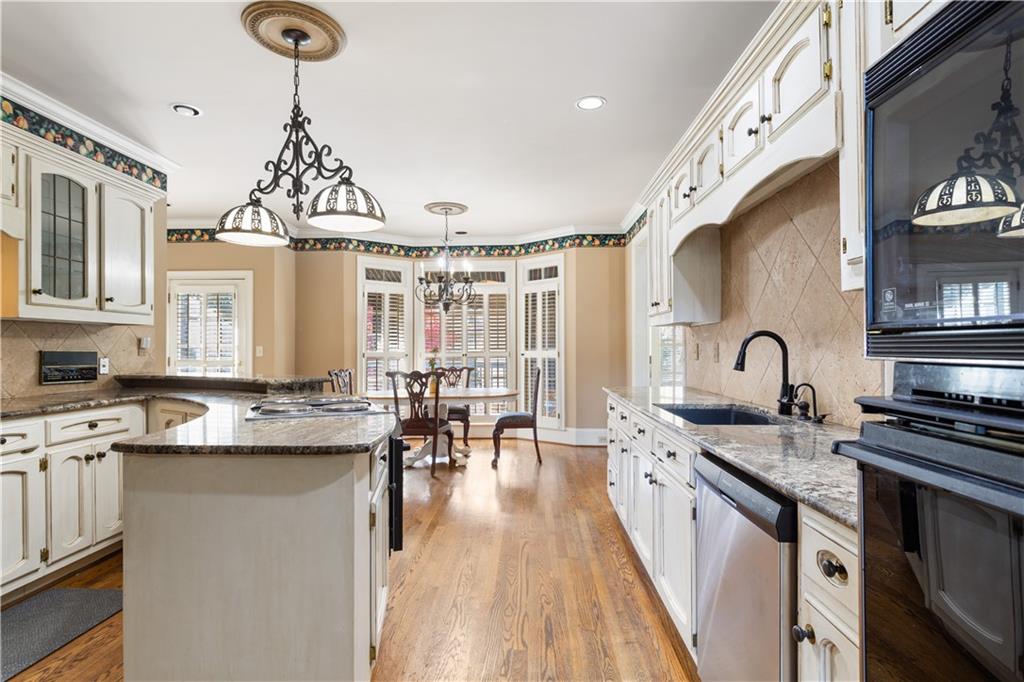 3910 Spalding Bluff Drive Peachtree Corners, GA 30092 - Photo 9 of 35 a kitchen with stainless steel appliances a stove a sink dishwasher and white cabinets with wooden floor