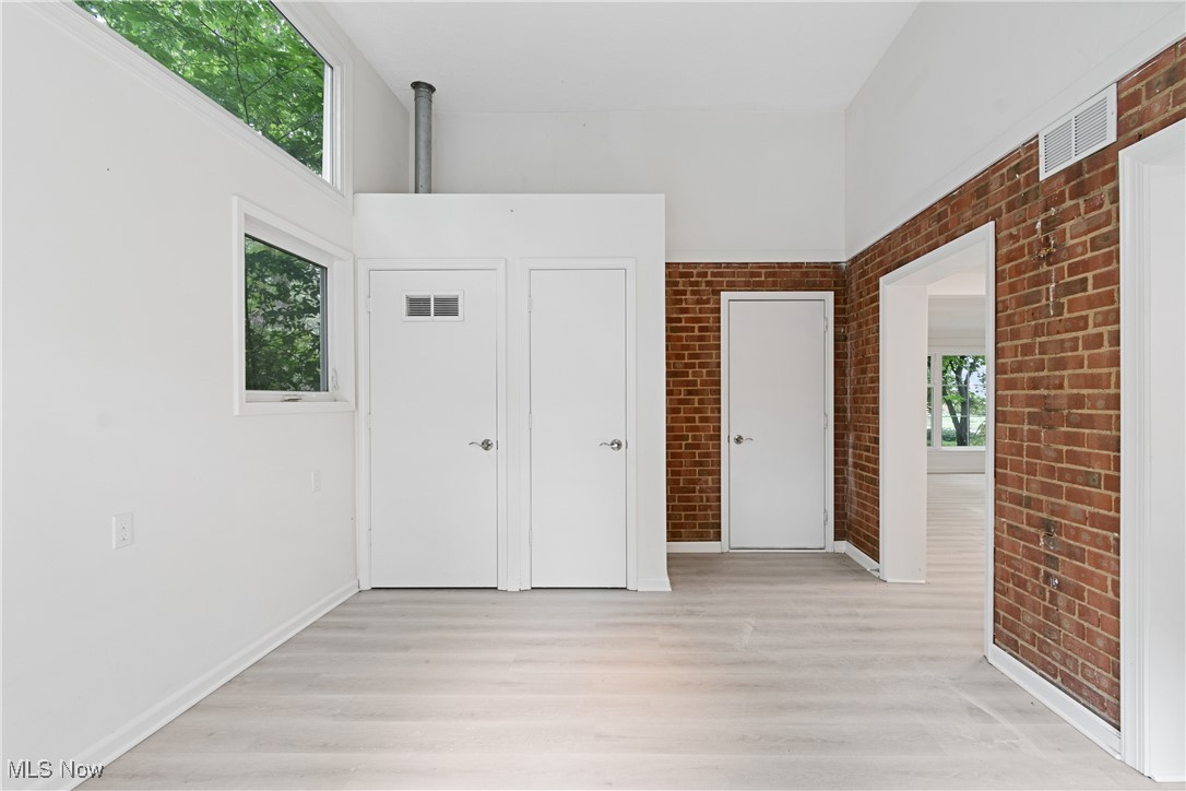 1057 Renfield Road Cleveland Heights, OH 44121 - Photo 13 of 30 Unfurnished bedroom featuring light wood-type flooring, a towering ceiling, and brick wall