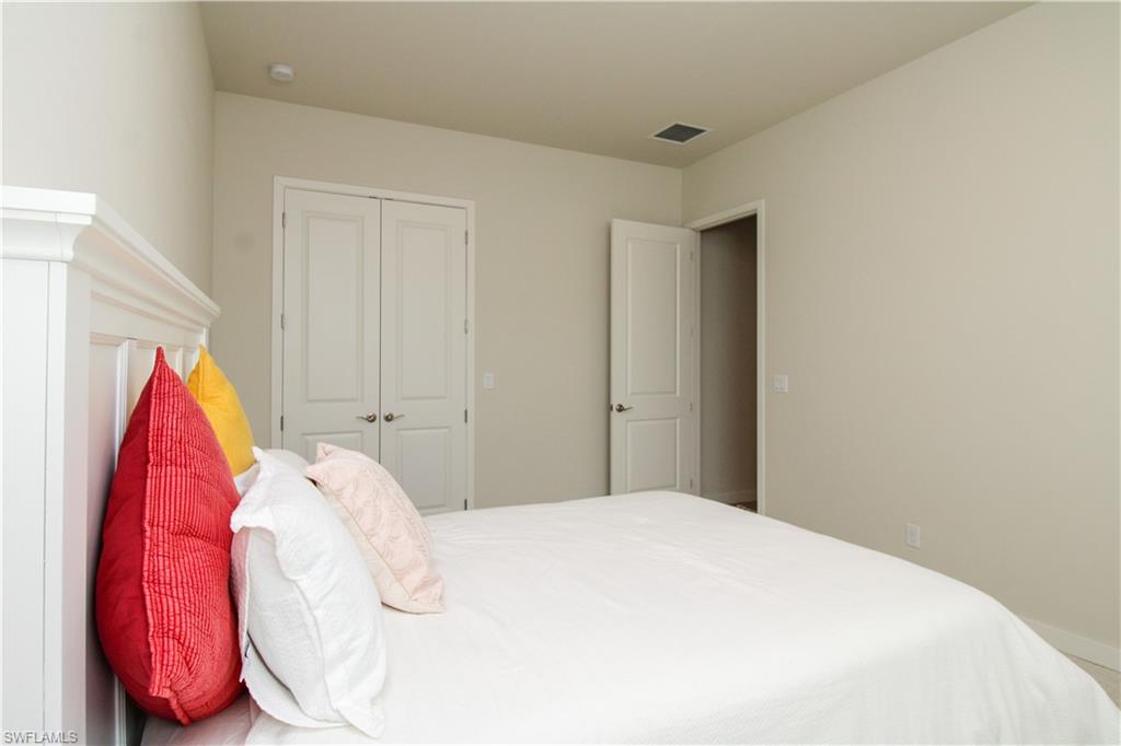 14803 Loggerhead Drive Naples, FL 34120 - Photo 19 of 50 a bedroom with a white bed and a chair