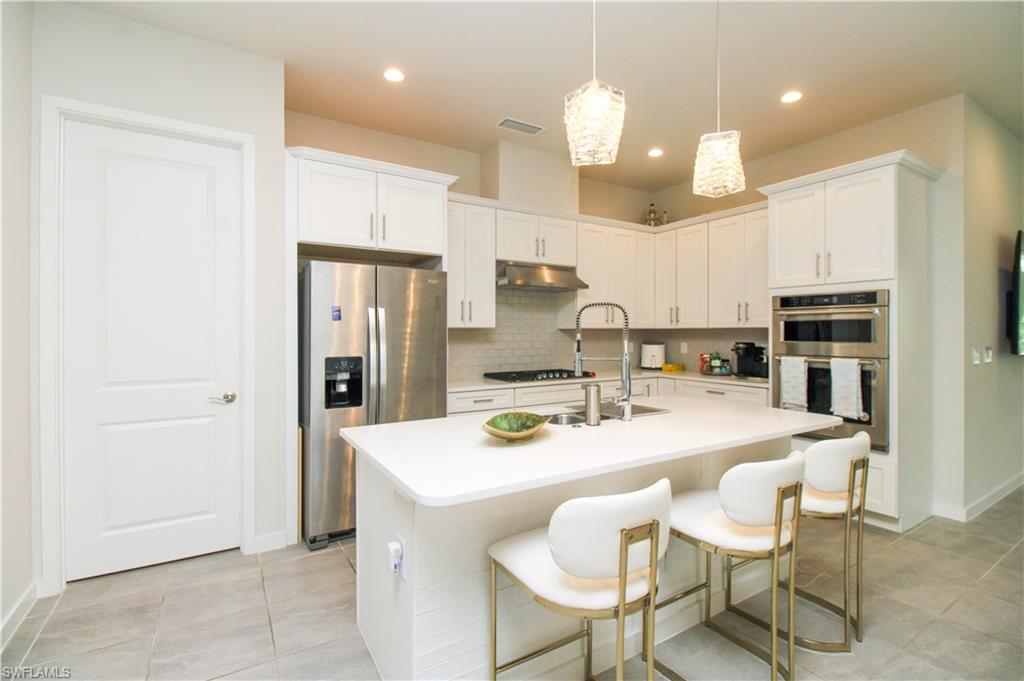 14803 Loggerhead Drive Naples, FL 34120 - Photo 24 of 50 a kitchen with a dining table chairs refrigerator and cabinets