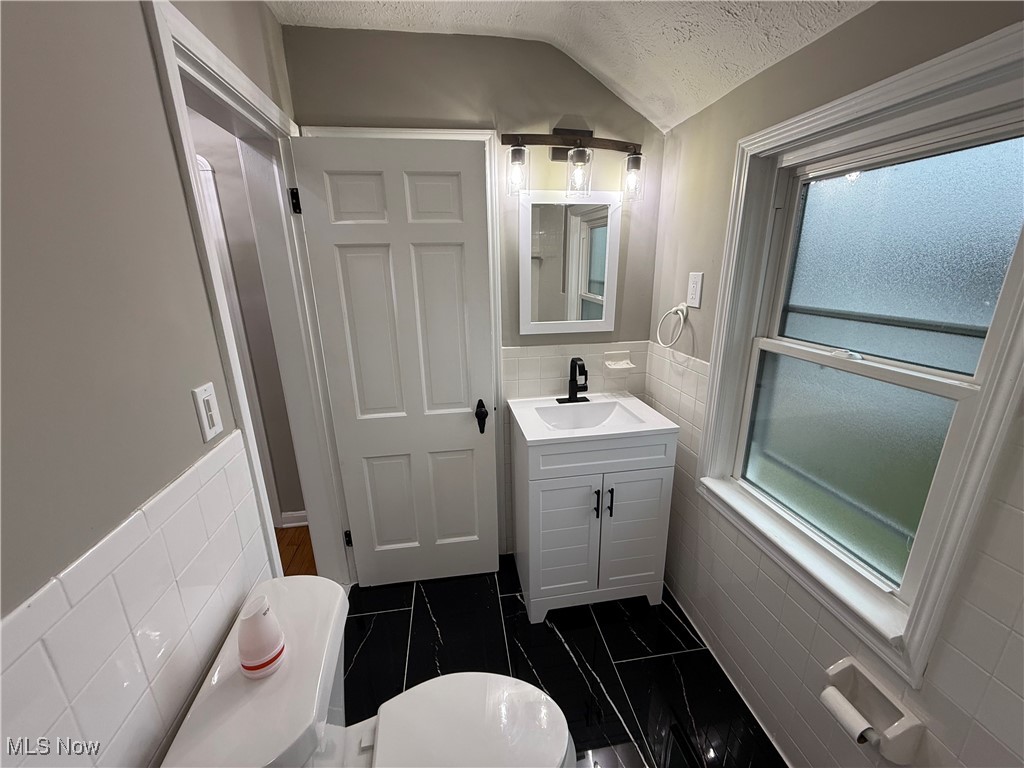 6807 Gerald Avenue Parma, OH 44129 - Photo 13 of 25 Half bath with a textured ceiling, tile walls, and vanity