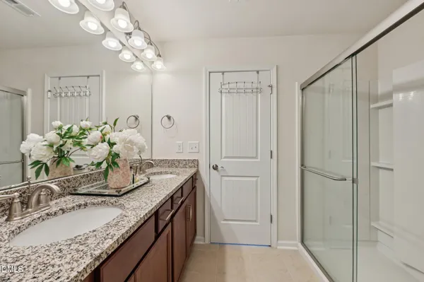 a bathroom with a granite countertop sink a mirror and a shower