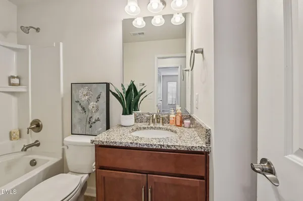 a white bath tub sitting next to a white toilet and vanity