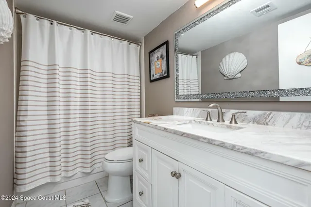 a bathroom with a granite countertop toilet sink and mirror