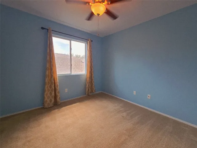 an empty room with a window and a fan