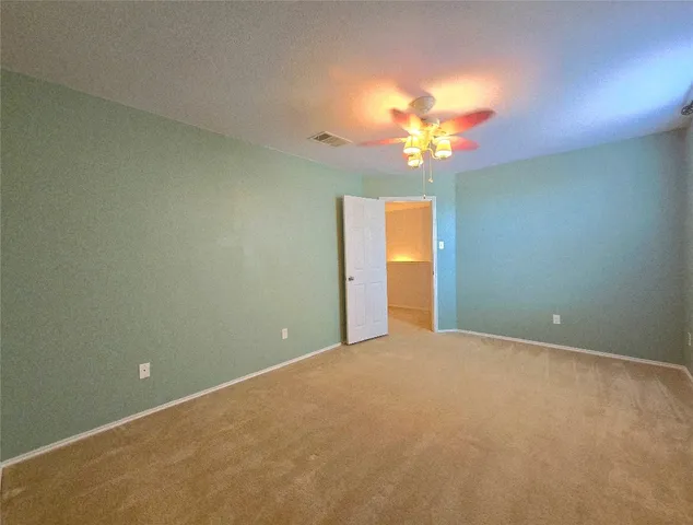 a view of an empty room with a chandelier fan