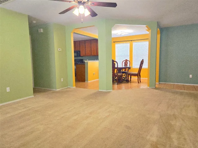 an empty room with chandelier fan and windows