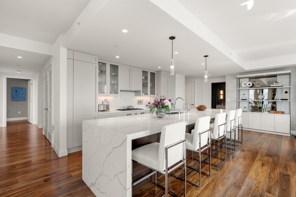 110 Sudbury Street, Unit 4002 Boston, MA 02114 - Photo 13 of 42 a kitchen with stainless steel appliances kitchen island granite countertop a dining table chairs and white cabinets