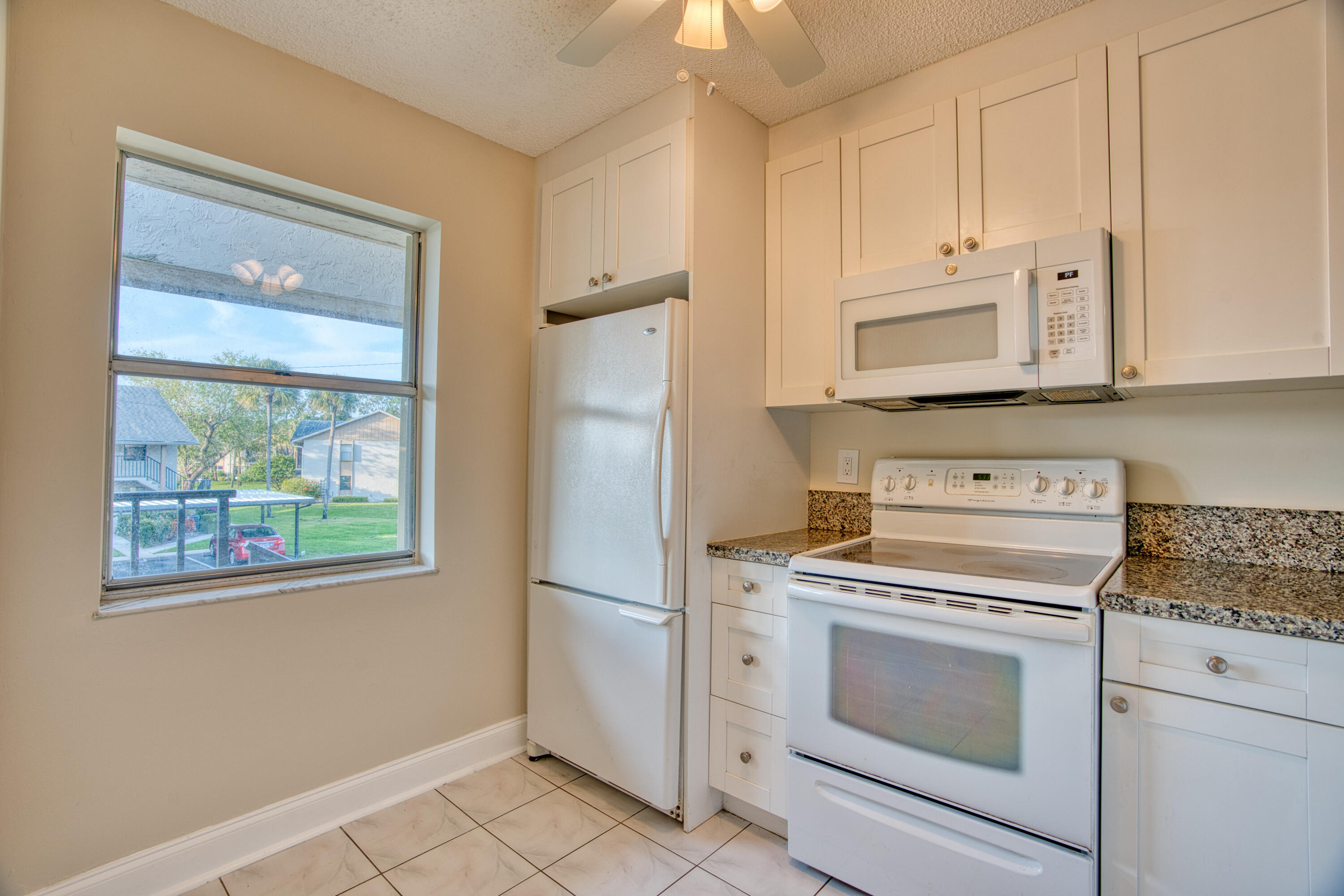 3151 Southeast Aster Lane, Unit 1306 Stuart, FL 34994 - Photo 12 of 27 a kitchen with white cabinets and white appliances